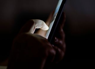 Cropped Hands Using Phone In Darkroom