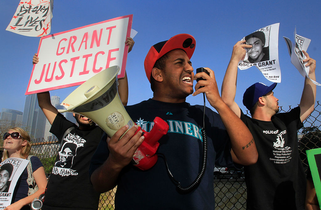 Protester Aaron Mallory (center) shouts his message into a bullhorn during a rally outside the LA C