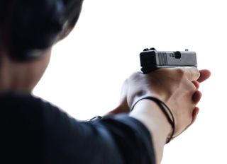 Close-Up Of Woman Shooting With Handgun Against White Background
