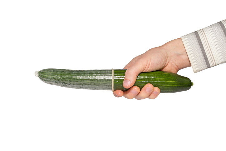 Holding a cucumber with a condom