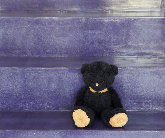 Black teddy bear sitting on the steps