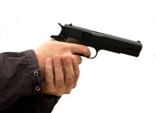 Cropped Hands Of Thief Holding Gun Against White Background