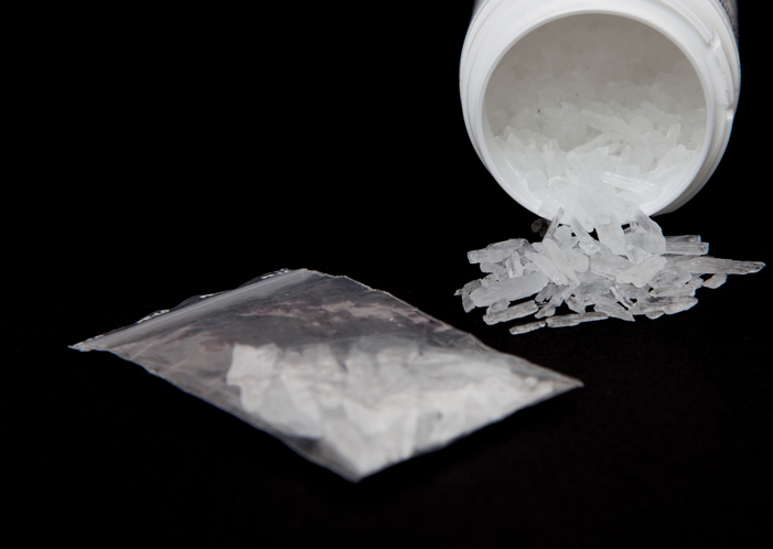 Close-Up Of Methamphetamine In Container And Plastic Bag Against Black Background