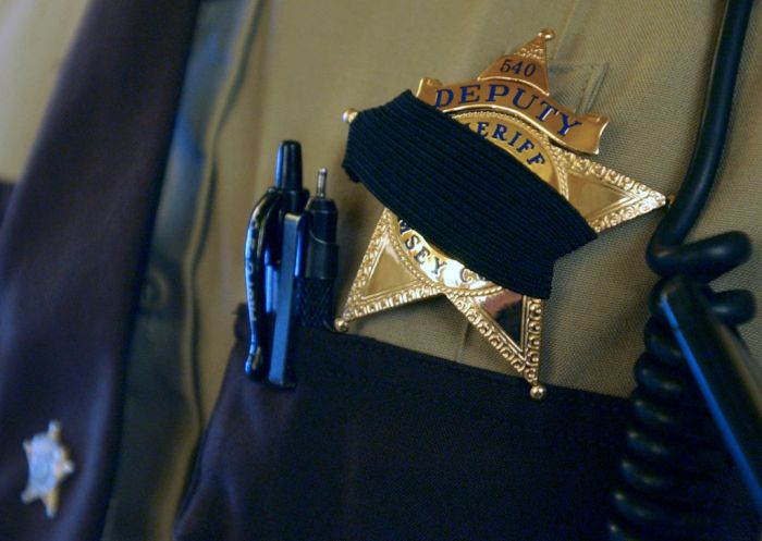 Joey McLeister/Star Tribune St. Paul,Mn.,Sat.,May 7, 2005--Ramsey County Deputy Sheriff Moon Chong wore a black band over his badge in memory of slain St. Paul Police Sergeant Gerald Vick. Chong stood guard at City Hall at a memorial for Vick at the bas