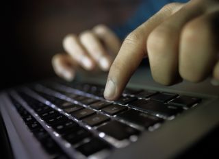 Hacker hand typing code on laptop
