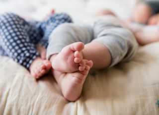 Feet of Caucasian twin baby girls laying on bed