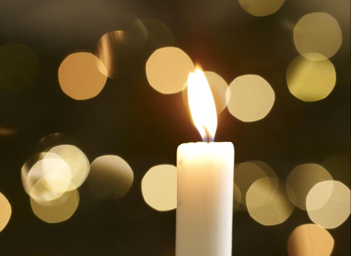 single candle with christmas lights in background