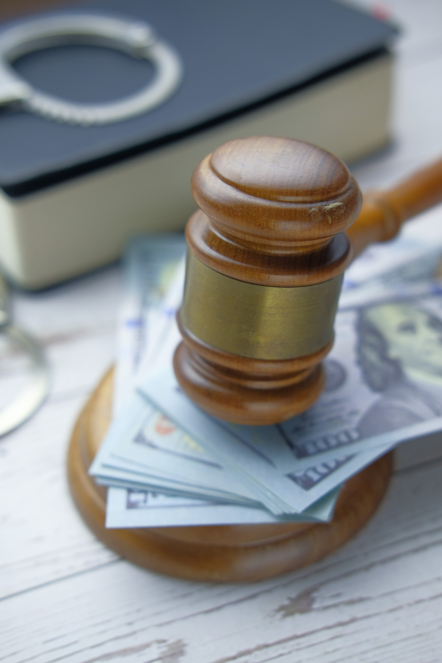 Gavel on cash with handcuff on table