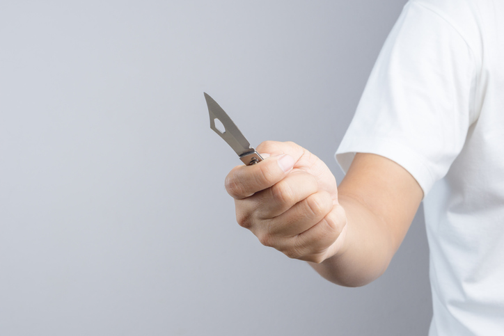 Midsection Of Man Holding Knife Against Gray Background