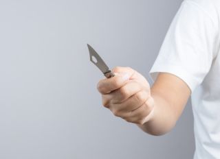 Midsection Of Man Holding Knife Against Gray Background