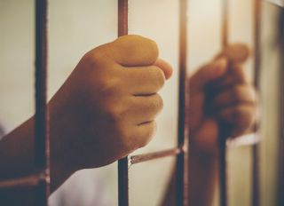 Cropped Hands Of Prisoner In Jail