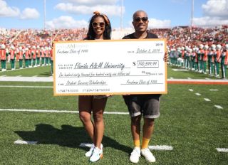 Nikki Foster and Walt Brown hold up nearly $200K donation check at FAMU homecoming