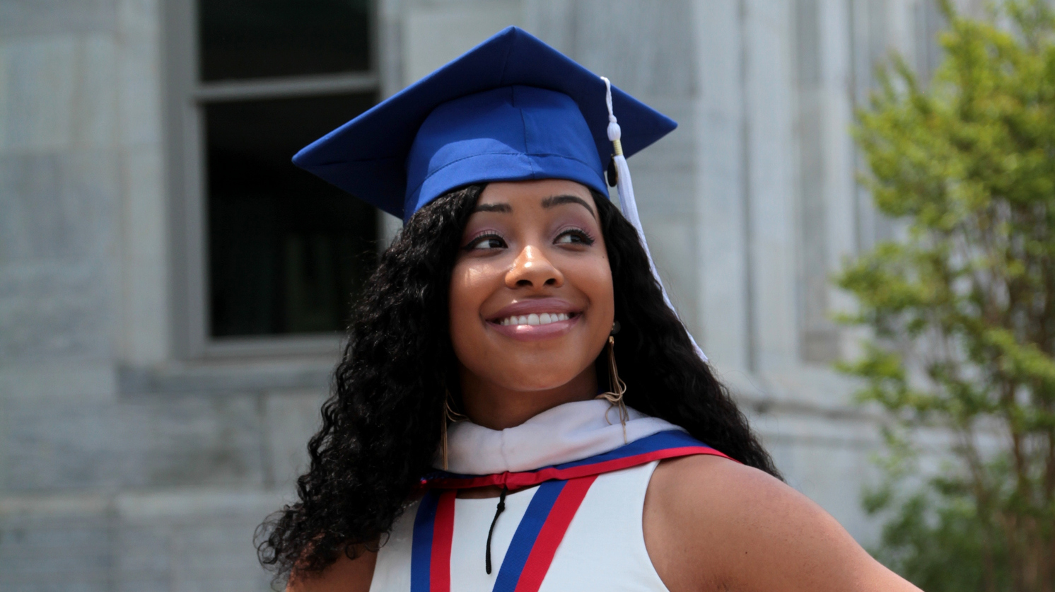 Woman In Mortarboard Standing Against Building - stock photo