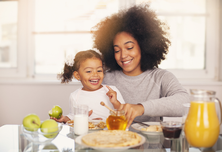 African-American young mother and daughter having breakfast