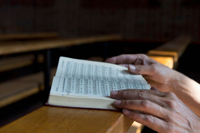 Hands on hymnbook on pew