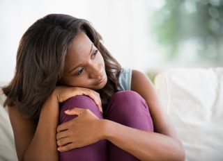 Black woman hugging her knees - stock photo
