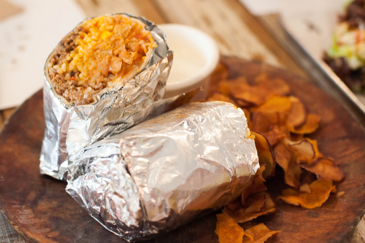 A close-up view of freshly made burrito on a wooden plate