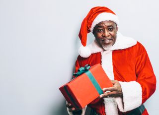 Santa Claus holding christmas gift on grey background