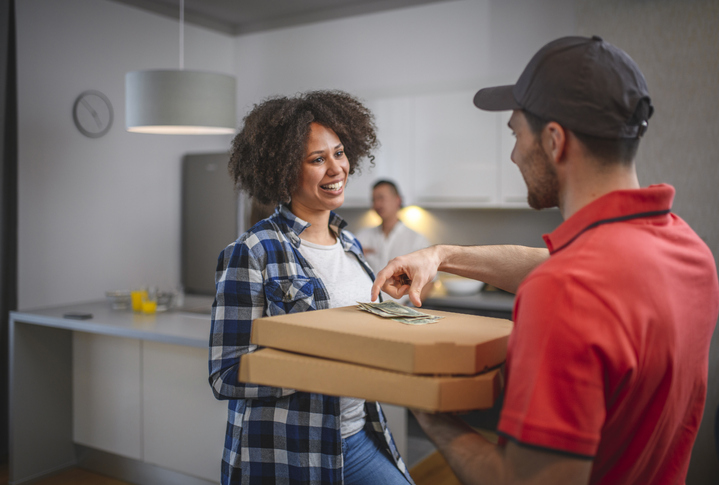 Young Man in Uniform Collecting Cash for Pizza Delivery