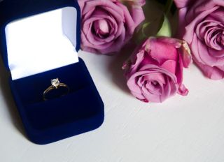 Engagement ring in a box and pink roses