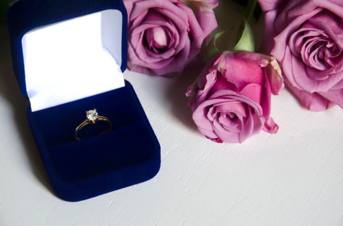 Engagement ring in a box and pink roses
