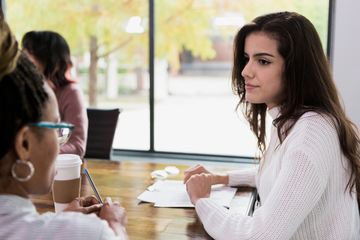 Mid adult manager listens to unrecognizable employee
