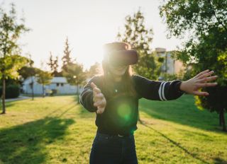 Young woman looking through VR headset in park