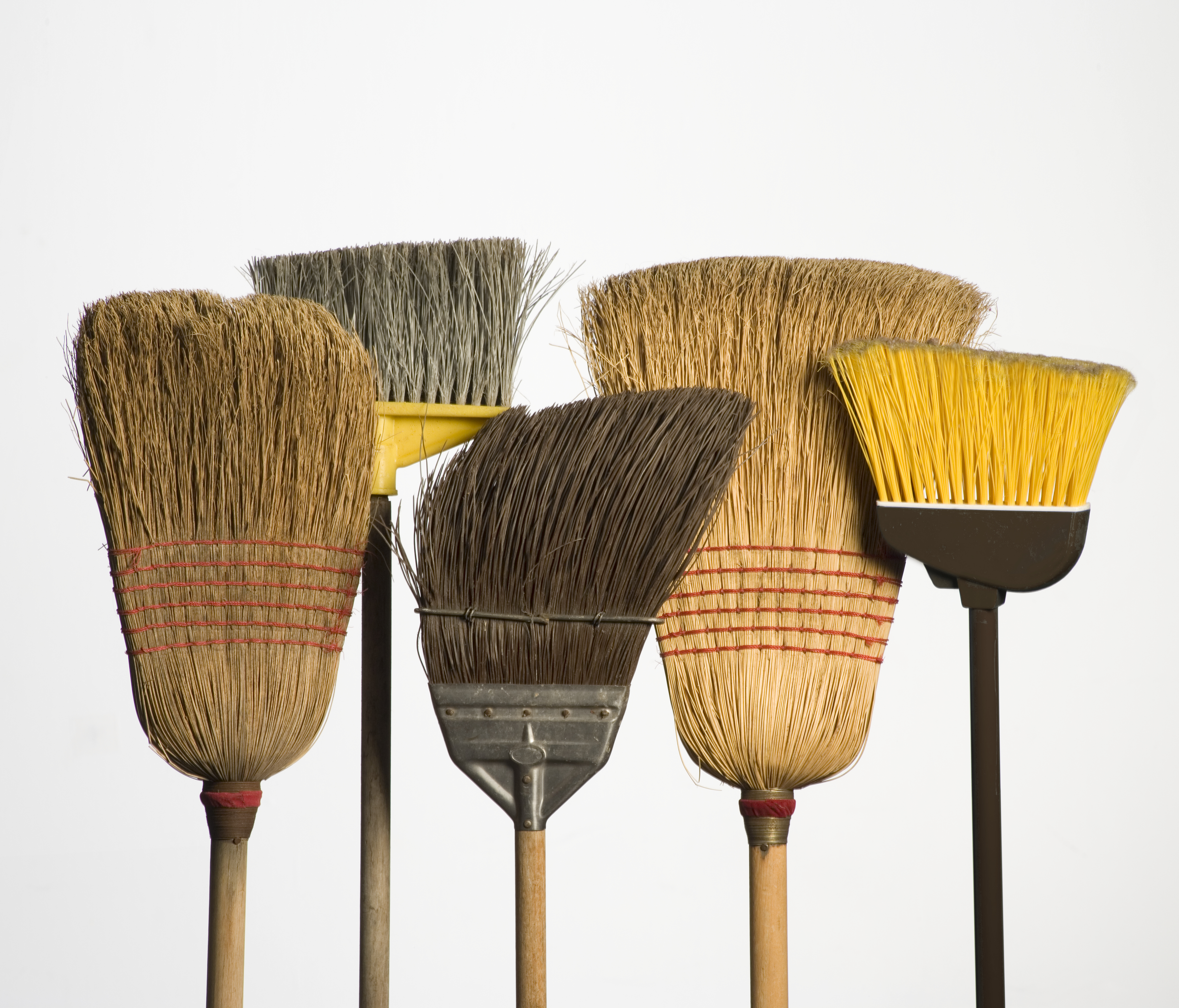 Five brooms side by side, still life, studio shot - stock photo