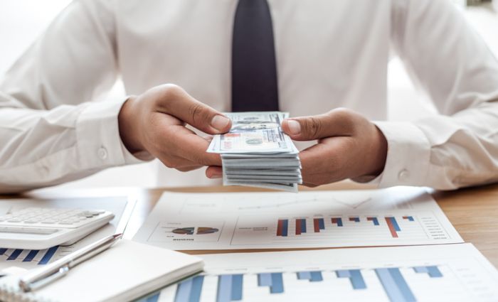 Midsection Of Man Holding Paper Currency On Table