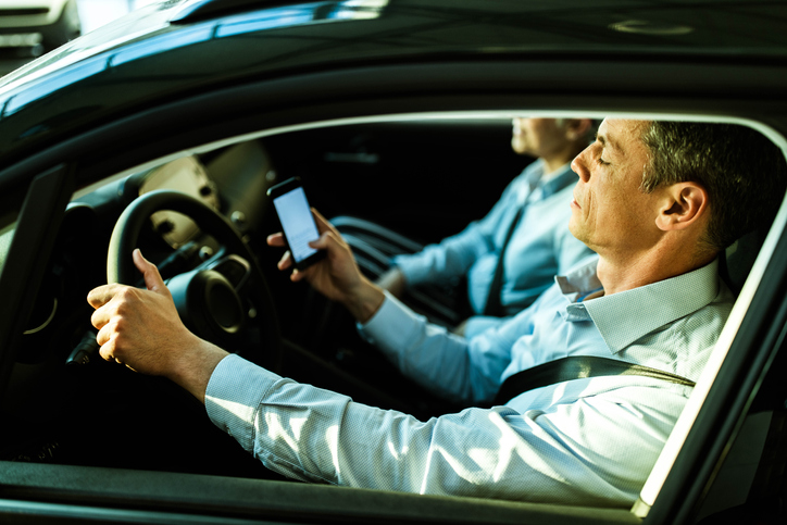 Mid adult man using cell phone while driving a car.