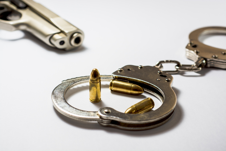 High Angle View Of Bullets And Handcuffs With Gun On White Background