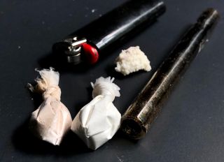 Cocaine, heroin, and crack with paraphernalia over a black background