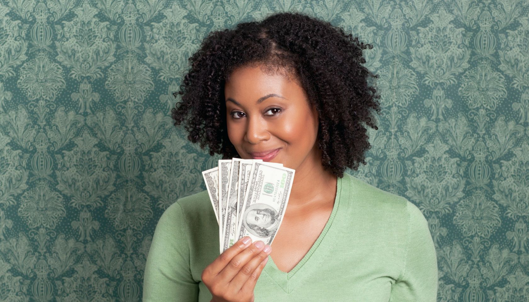 Woman holding currency in front of laptop - stock photo