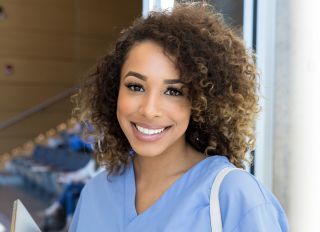 Smiling nursing student in scrubs leaves lecture hall - stock photo
