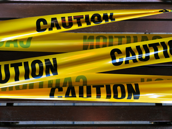Social distancing enforced with yellow barrier tape across public bench at train station platform