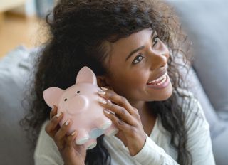 Beautiful black woman holding her pinbk piggy bank trying to guess how much money she has
