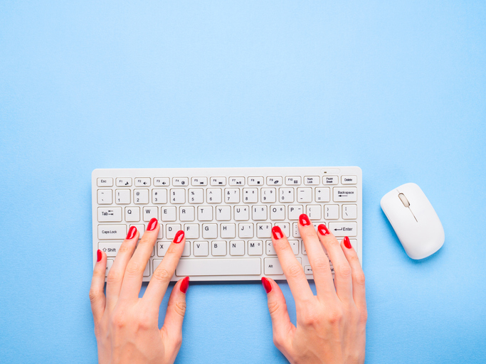 Close-Up Of Woman Hands Using Computer Keyboard On Blue Background