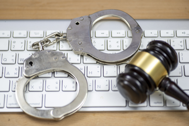 Laptop, wooden gavel and handcuffs on light table, closeup. Cyber crime