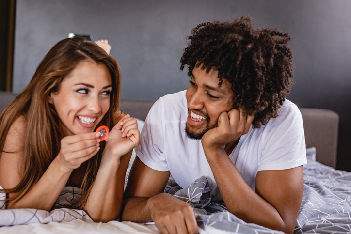 men and women are discussing the use of condoms. young couple in bed
