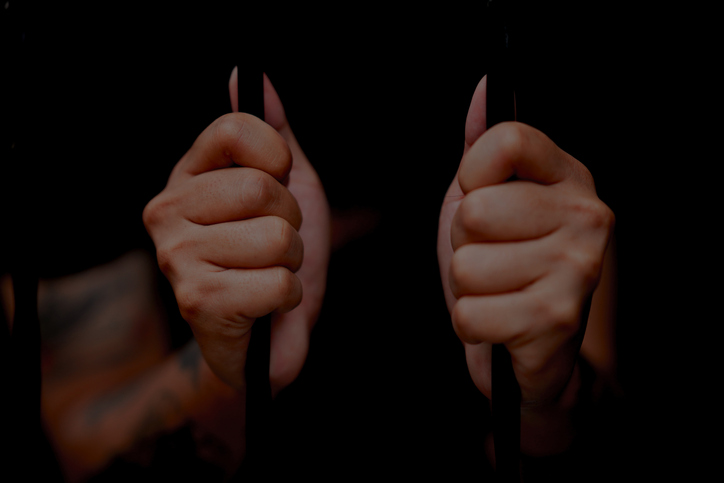 Selective focus on palm hand of Inmates being stuck in jail isolated over black background