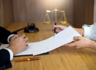 Cropped Hands Of Lawyer Showing Businessman To Sign Paper On Table