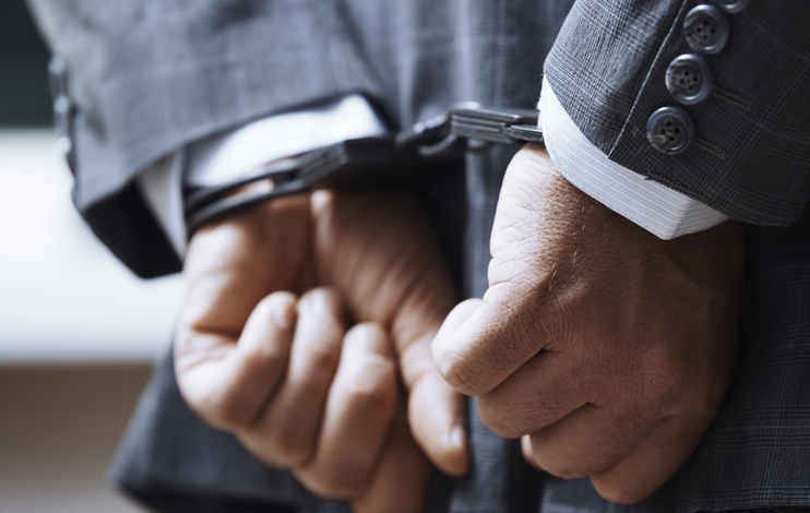 Hands of arrested businessman wearing handcuffs