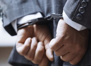 Hands of arrested businessman wearing handcuffs