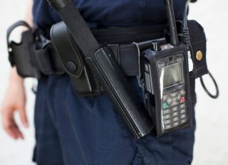 Midsection of a police officer with walkie-talkie and night stick on equipment belt