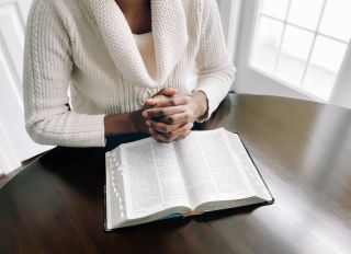 Woman Reads Bible at Kitchen Table