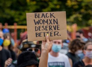A participant holding a Black Women Deserve Better sign at...