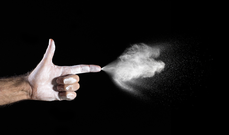 Hand of a man that appears with the finger in the form of a gun shooting on a black background.