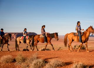 Four Young Native American Navajo Brothers and Sisters Riding their Horses Bareback in the Northern Arizona Monument Valley Tribal Park At Dusk Together