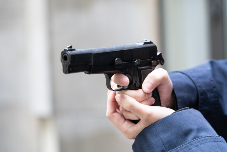 Cropped Hand Of Police Holding Handgun Outdoors