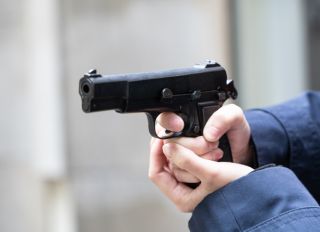 Cropped Hand Of Police Holding Handgun Outdoors